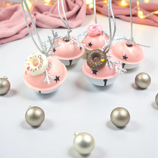 Decorative necklaces with donut pendants on a white surface with Christmas ornaments.