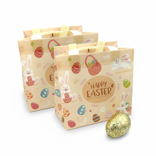 Two Easter-themed gift bags with decorative elements and a chocolate egg on a white background.