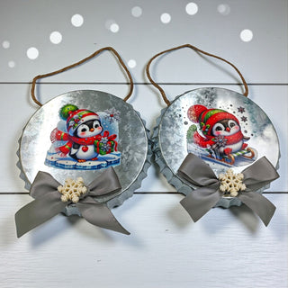 Two Christmas ornaments with penguins and ribbons on a white background