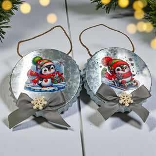 Two Christmas-themed penguin ornaments with ribbons on a light background.
