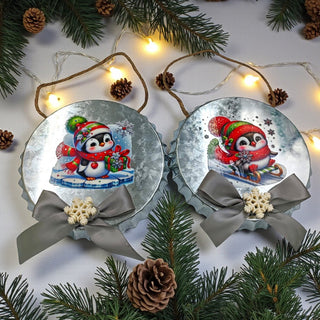 Two Christmas ornaments with penguins and ribbons on a white background