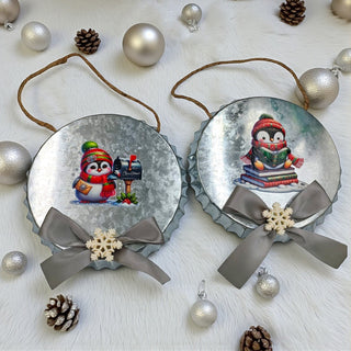 Two Christmas ornaments with penguins and ribbons on a white background