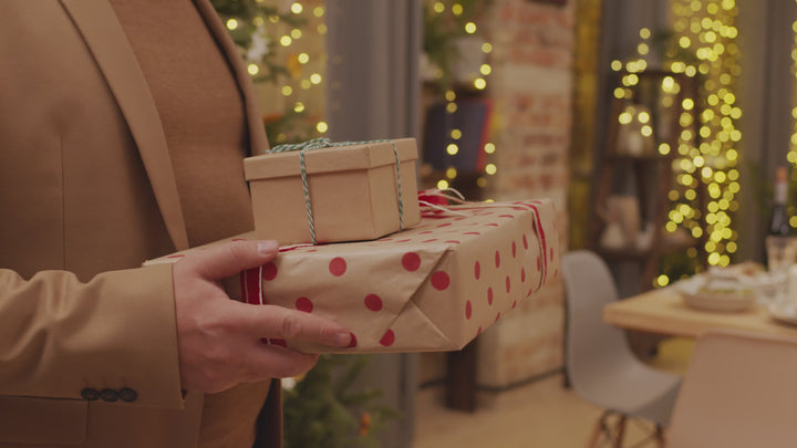 man holding presents in front of a festive backdrop