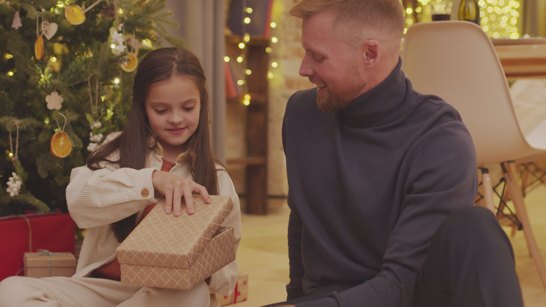 dad and daughter in front of a christmas tree, opening presents