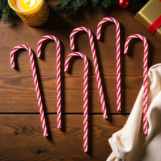Red and white striped candy canes on a wooden surface with Christmas decorations.