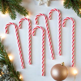 Red and white candy canes on a light background with Christmas decorations.