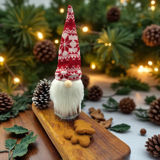 Decorative gnome with a red and white hat on a wooden board with pinecones and lights in the background