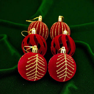 Red baubles with gold leaf patterns on a green fabric background