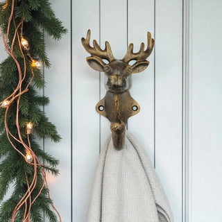 Decorative deer head hook with a towel on a wall with Christmas decorations.