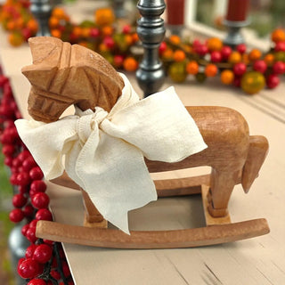 Wooden rocking horse with a white bow on a blurred festive background