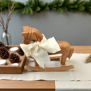 Wooden rocking horse with a bow on a table with decorative items