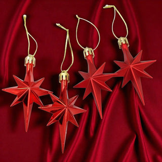 Red star-shaped Christmas ornaments with gold hooks on a red fabric background