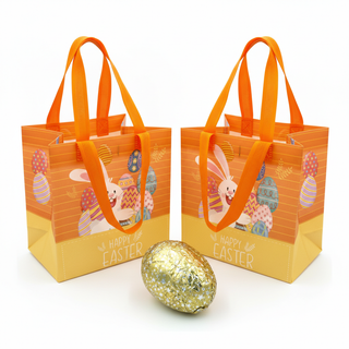 Two Easter-themed gift bags with orange handles and a gold glittery egg on a white background.