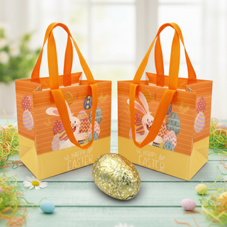 Two Easter-themed gift bags with orange handles on a wooden surface with decorative eggs.