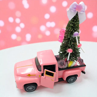 Pink toy truck with a Christmas tree and decorations on a pink background
