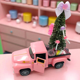 Pink toy truck with a Christmas tree on a pink surface