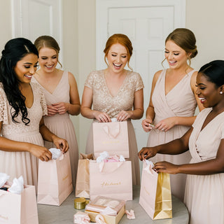 Five women in matching dresses opening gift bags together.
