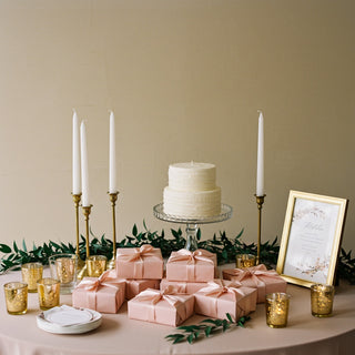Decorative table setting with a cake, candles, and gift boxes on a beige background