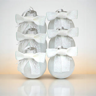 Decorative Christmas ornaments with glittery finish and white bows on a gradient background