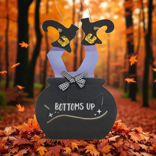 Halloween-themed decoration with witch hats and a cauldron in an autumn forest setting.