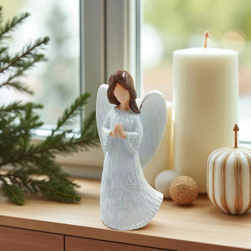 Decorative angel figurine on a table with candles and Christmas decorations.